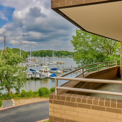 A balcony overlooking a marina with sailboats, surrounded by lush trees and under a partly cloudy sky, offering a serene water view.