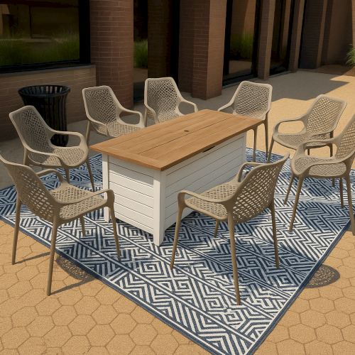Outdoor dining set with eight chairs and a rectangular table on a patterned rug, surrounded by brick walls and greenery.